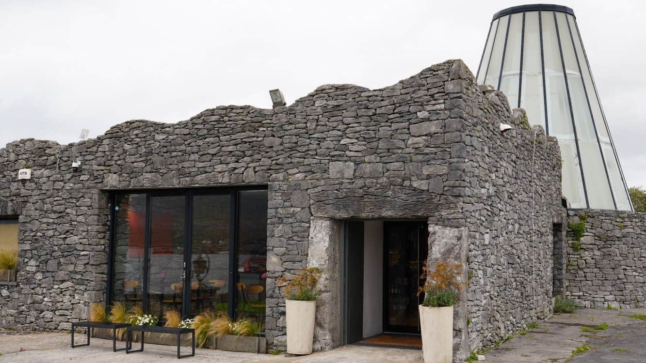Stone built exterior of a building with large glass dome feature in the background