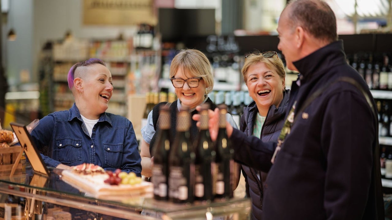 Four people standing at a counter with wine and food on it