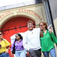 Group of people smiling leaving a building with red arched doors
