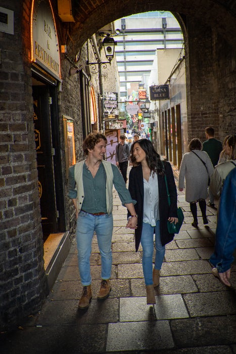 A couple walking through the Temple Bar archway in Dublin city