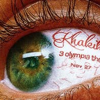 Very close up view of a green eye with long dark lashes and red text written in the white part of the eye