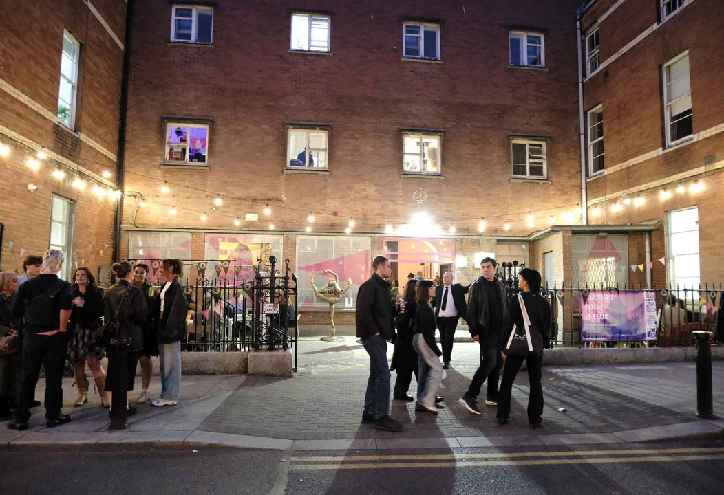 Exterior of a building at night with a courtyard and people and lights