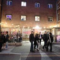 Exterior of a building at night with a courtyard and people and lights