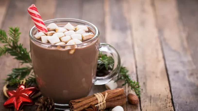 A clear mug of hot chocolate with small marshmallows on the surface