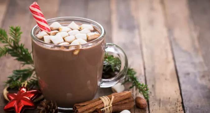 A clear mug of hot chocolate with small marshmallows on the surface