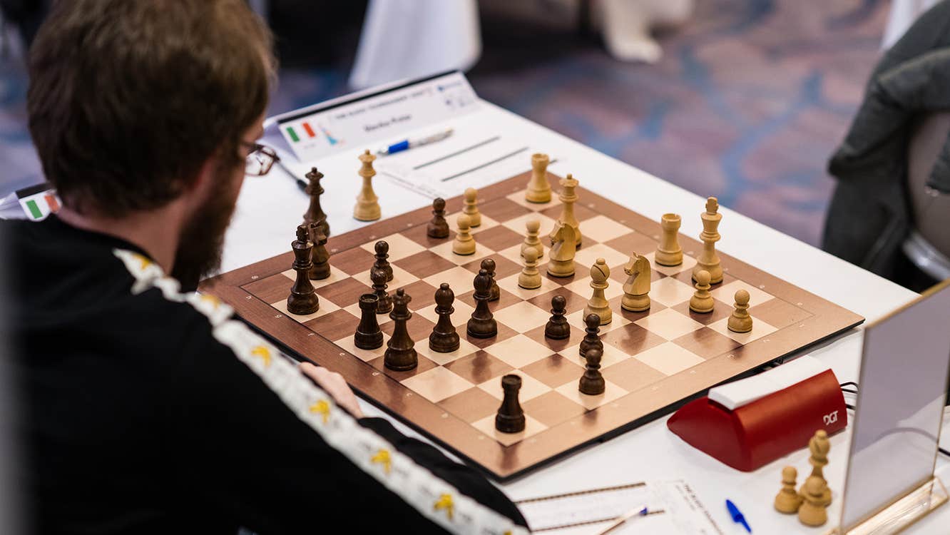 Chess player at board analysing position as black
