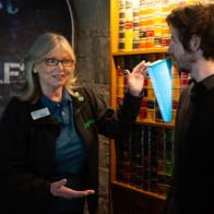 A tour guide is talking to 2 people standing beside an exhibit.
