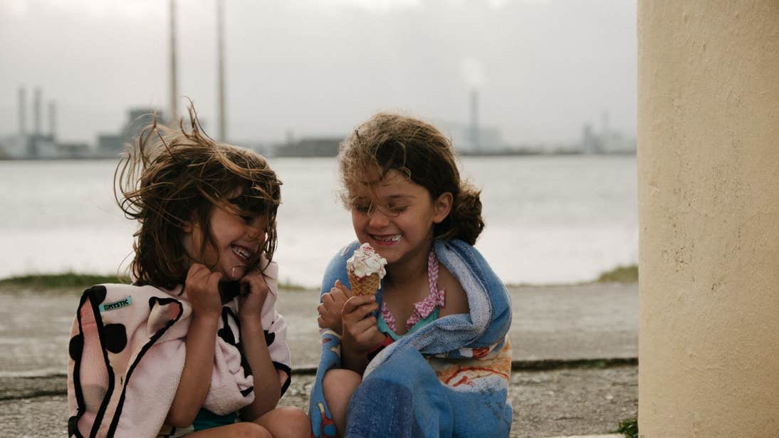 Two young girls enjoying ice cream by the sea in Dublin.
