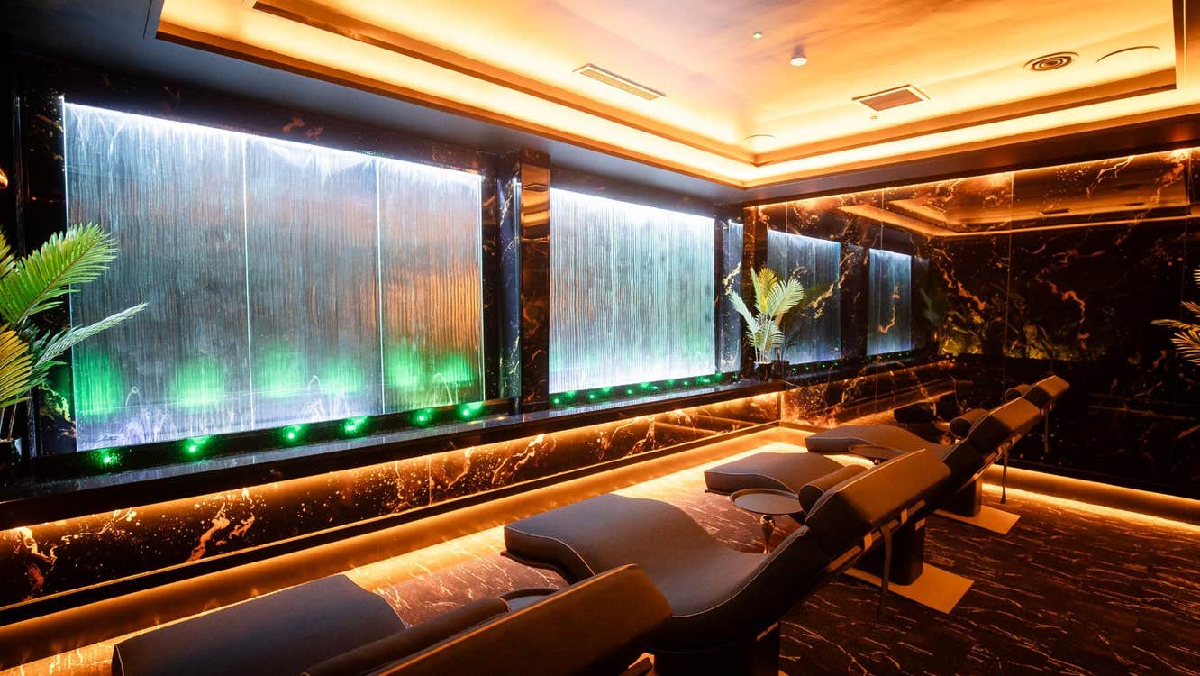 Four comfortable lounge seats in a spa facing a wall with a water feature