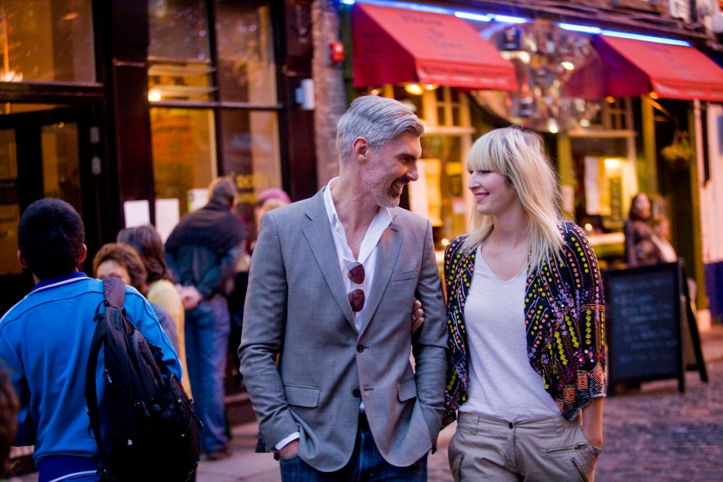 A couple walking hand in hand down a cobble street in Temple Bar, Dublin.