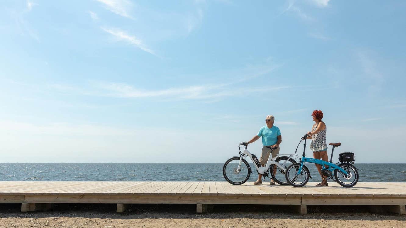 Two people with bikes on a boardwalk on a beach on a sunny day