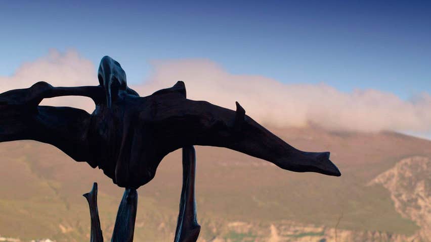 A sculpture in bog oak with hills of Achill in background giving the impression of a bird flying