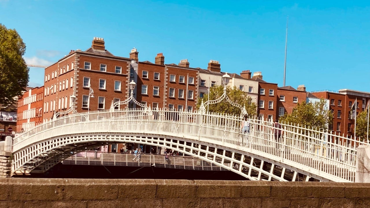 White bridge with people walking across and red brick buildings in the background