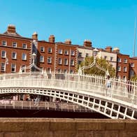 White bridge with people walking across and red brick buildings in the background