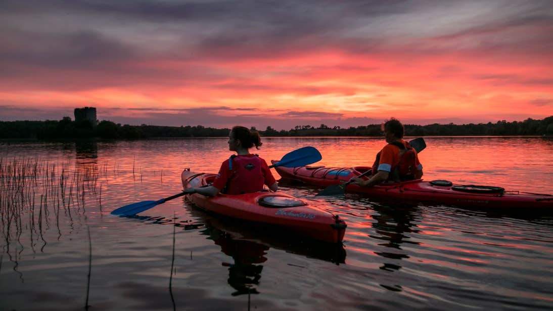 People kayaking  through still waters with beautiful sunset views