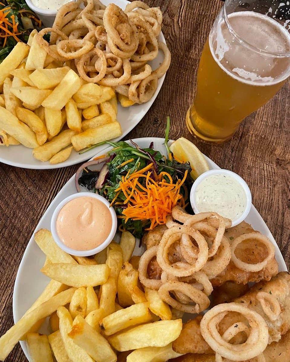 Two plates of fried calamari and chips, with a pint of beer.