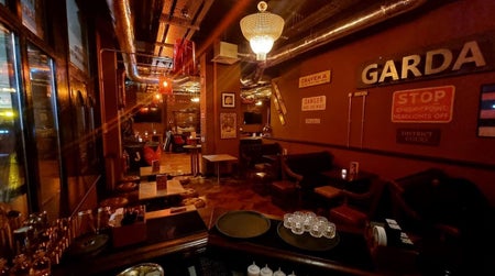 Dark red and wooden inside of a pub with tables and chairs and old signage on the walls