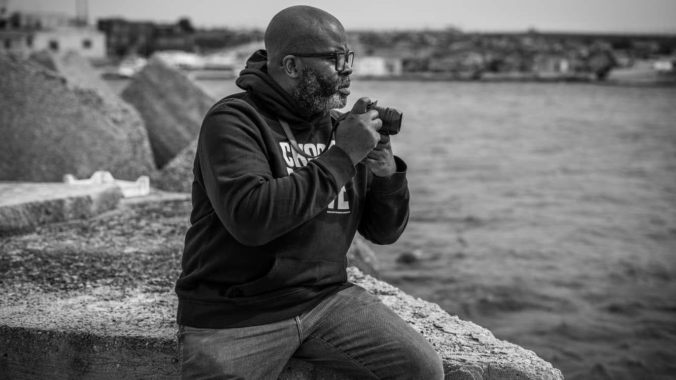 A man with a camera next to a body of water.