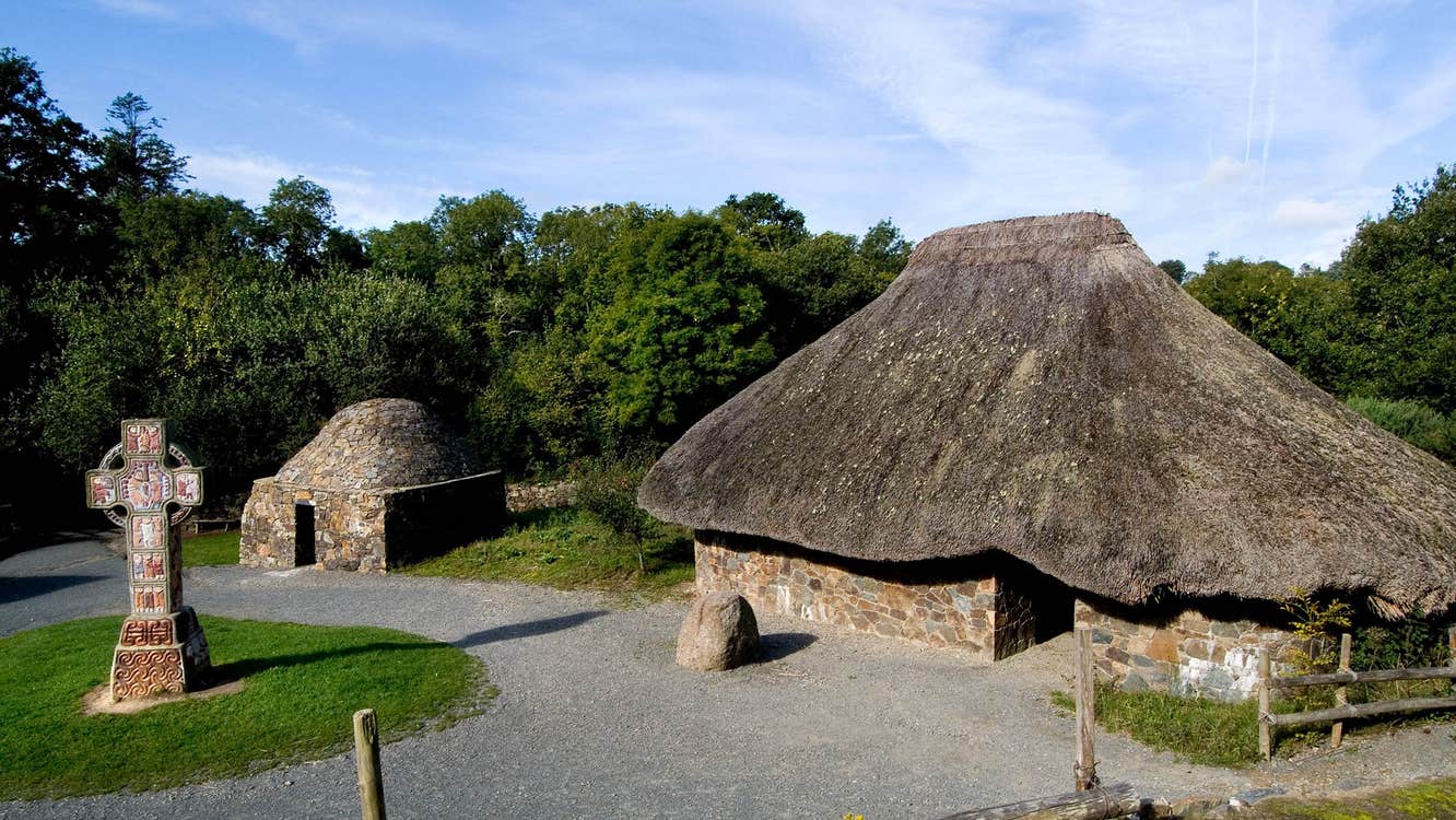A high cross and ancient stone settlements at the Irish National Heritage Park in County Wexford.