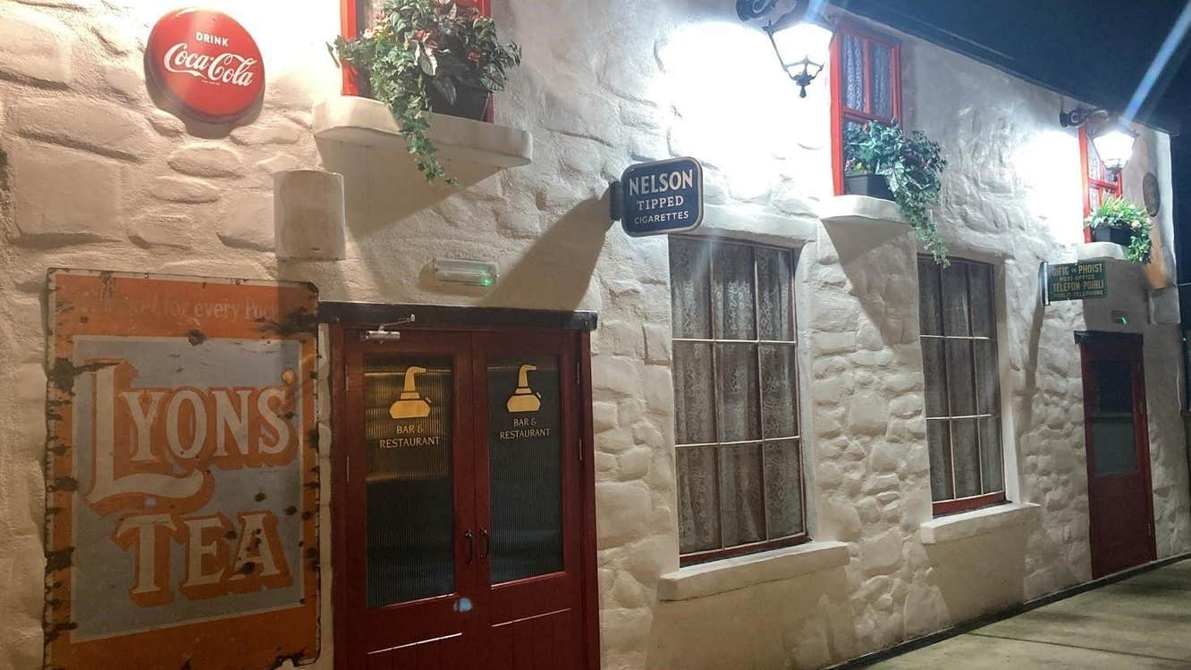 White exterior of an old pub with vintage looking signage displayed