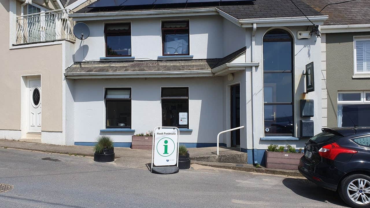 Exterior of a two storey building on a street with a tourist information sign outside