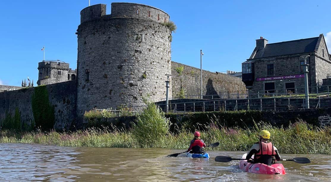 Two people kayaking along King John's Castle in Limerick city.