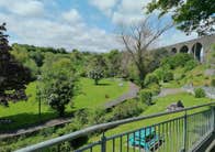 StepsBackThruTime Guided Walking Tour Experiences view of a park area overlooked by a grey stone bridge with arches