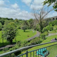 StepsBackThruTime Guided Walking Tour Experiences view of a park area overlooked by a grey stone bridge with arches