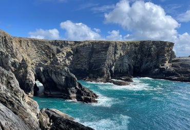 A view of cliffs and a sea arch under a blue sky