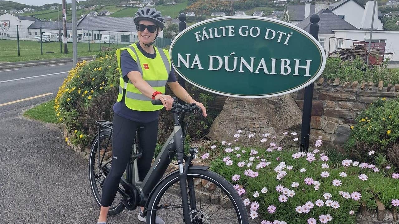 A lady on an ebike stopped at a village sign