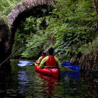 An Emerald Outdoors kayak passing under a bridge