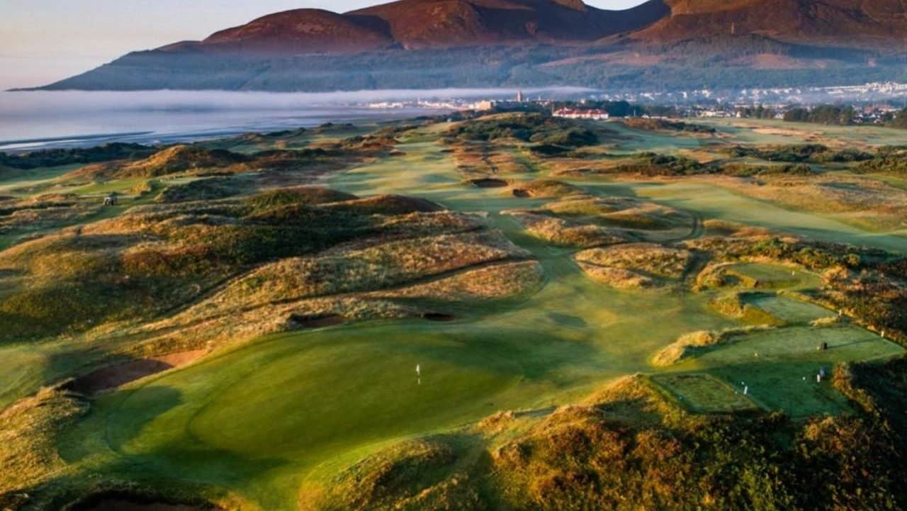 Drone image of a links golf course with mountains in the background