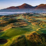 Drone image of a links golf course with mountains in the background