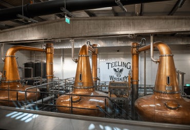 Three large copper pot stills in a whiskey distillery