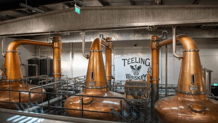 Three large copper pot stills in a whiskey distillery