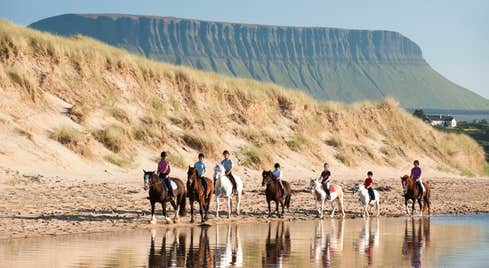 People horse riding on the beach in County Sligo