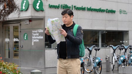 A tourist standing outside Dublin Tourist Information Centre Barnardo Square reading a map