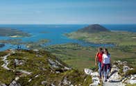 Two people hiking Diamond Hill in Connemara National Park with a view of the Connemara lakes