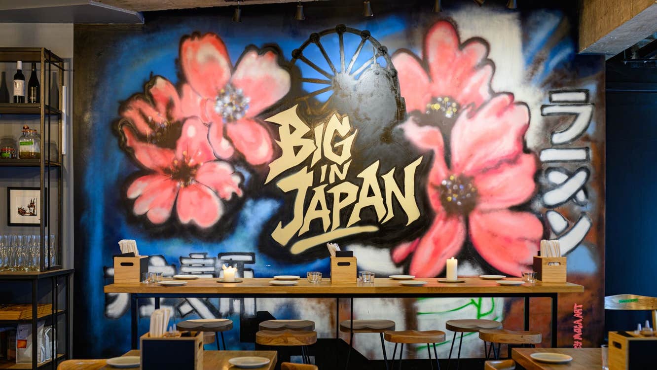 Dining area in the restaurant with a colourful Japanese mural on the wall