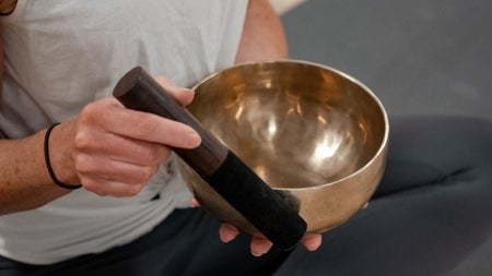 A person in a yoga pose holding a sound bowl