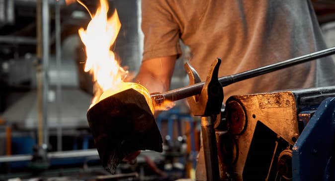 Person holding a piece of crystal on an iron poker over a large flame