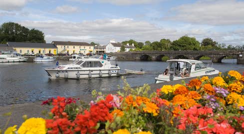 Boats cruising on the River Shannon with a backdrop of beautiful flowers