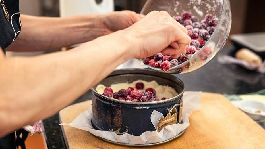 Dublin Cookery School, Festive Supper Club - a pair of hands tipping red berries into a cake tin.
