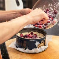 Dublin Cookery School, Festive Supper Club - a pair of hands tipping red berries into a cake tin.