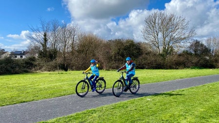 Two people out cycling wearing blue high visibility waistcoat and blue bike helmets