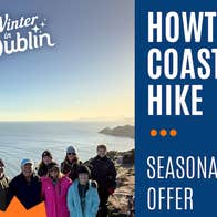 A group of smiling people outdoors with the sea in the background.
