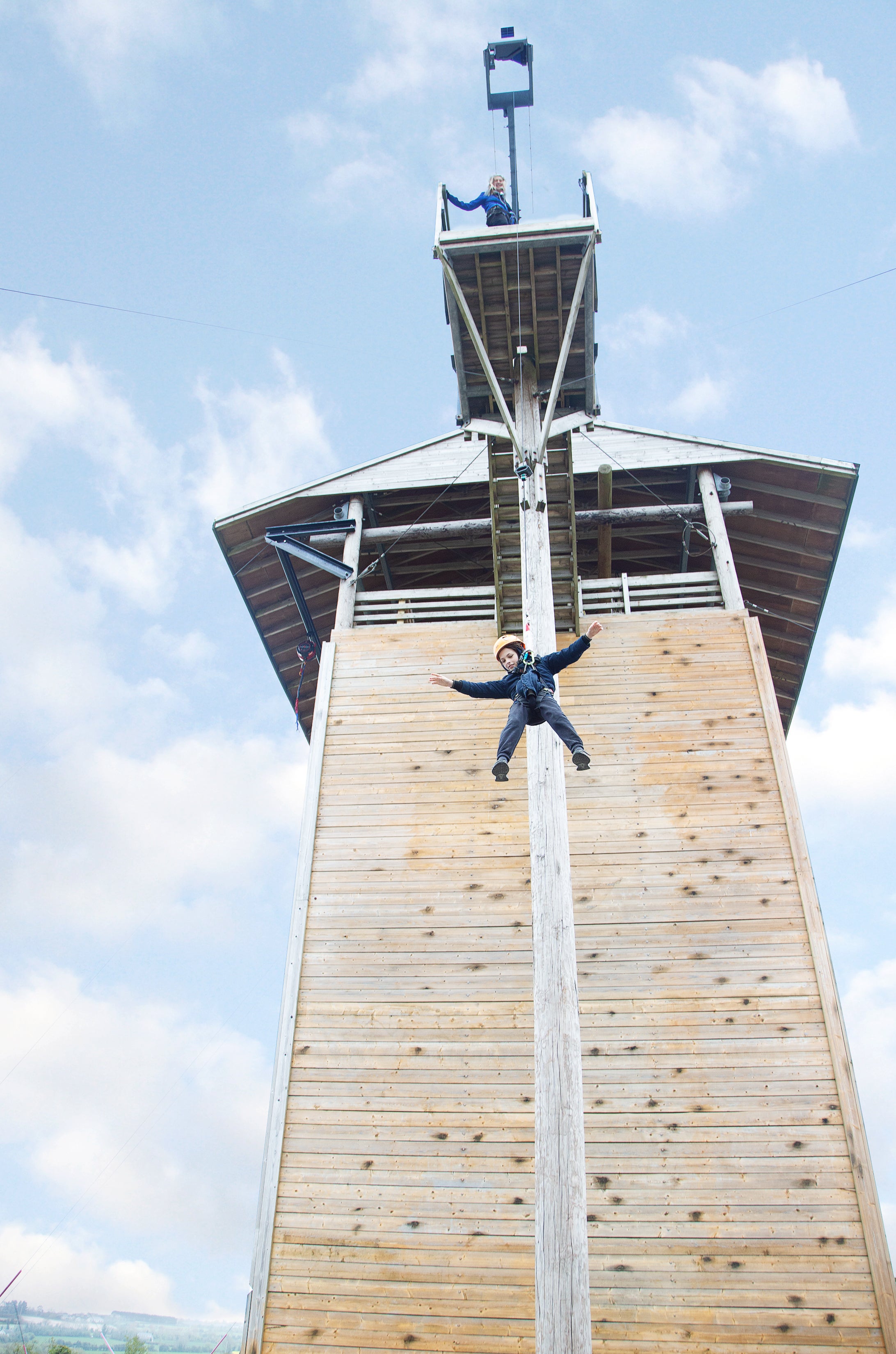 A boy descending by wire from a high climbing wall