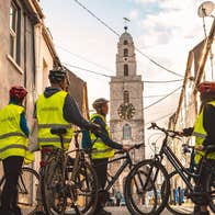 Group of people with bikes and hi vis vests standing facing a clock tower