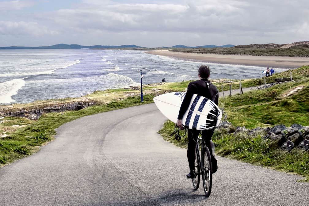 Surfer cycling down to Tullan Strand, Bundoran, County Donegal