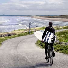 Surfer cycling down to Tullan Strand, Bundoran, County Donegal